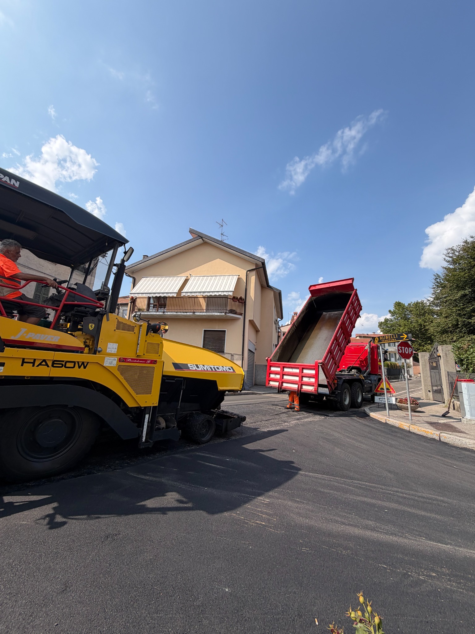 Finitrice e autocarro impegnati in un cantiere stradale
